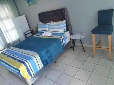 a bedroom with a bed and a blue chair at Gardenia Guesthouse in Cape Town