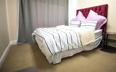 a bed with a red headboard and pillows on it at Gardenia Guesthouse in Cape Town
