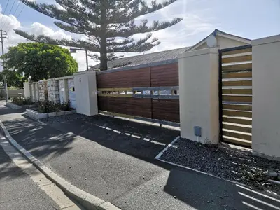 a building with a wooden fence next to a street at Coastal Cozy 1 in Cape Town