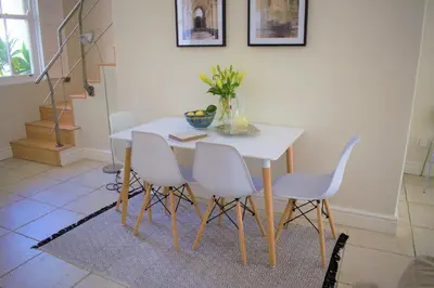 a dining room table with white chairs and a white table at Le Habitat 6 in Franschhoek