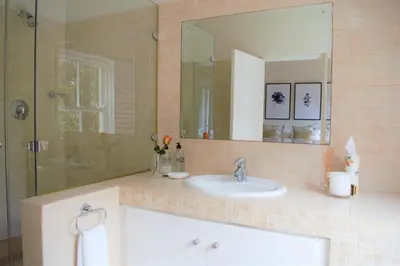 a bathroom with a sink and a shower with a mirror at Le Habitat 6 in Franschhoek