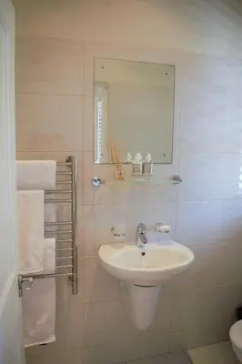 a white bathroom with a sink and a mirror at Le Habitat 6 in Franschhoek