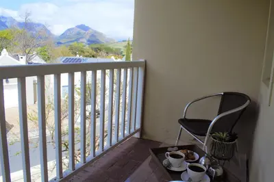 a balcony with a chair and cups on a table at Le Habitat 6 in Franschhoek