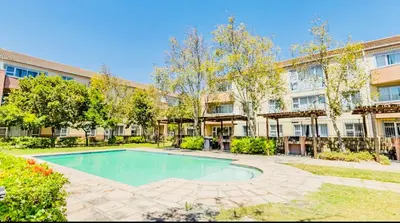 an apartment building with a swimming pool in a yard at Modern charm in Pinelands in Cape Town