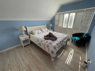 a small bedroom with a bed and a chair at De Blauwvoet - Flamingo Apartment in Cape Town