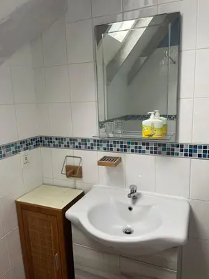 a white bathroom with a sink and a mirror at De Blauwvoet - Dolfyn (Sunset Beach) in Cape Town