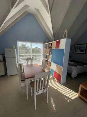 a dining room with a table and chairs and a bedroom at De Blauwvoet - Dolfyn (Sunset Beach) in Cape Town