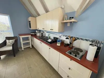 a kitchen with white cabinets and a counter top at De Blauwvoet - Dolfyn (Sunset Beach) in Cape Town