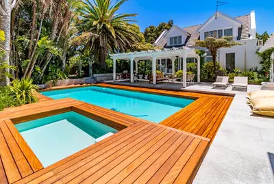 a swimming pool with a wooden deck and a house at The Atrium in Somerset West
