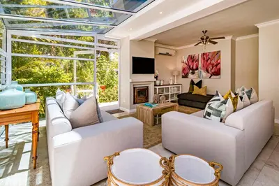 a living room with white furniture and a large window at The Atrium in Somerset West