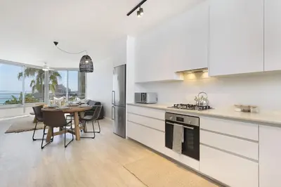 a kitchen with white cabinets and a table with chairs at Welgelegen 608 in Strand