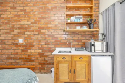 a kitchen with a brick wall and a sink at Blouberg Studio Apartments in Bloubergstrand