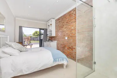 a bedroom with a bed and a brick wall at Blouberg Studio Apartments in Bloubergstrand