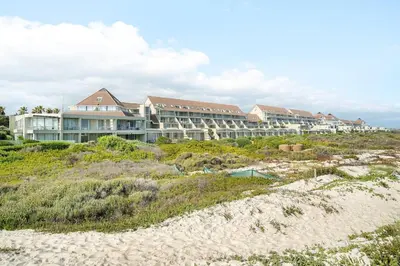 a large hotel on the beach next to the beach at Dolphin Beach beachfront apartment, 3 bedroom-6 persons in Cape Town