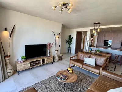 a living room with a couch and a flat screen tv at Dolphin Beach beachfront apartment, 3 bedroom-6 persons in Cape Town