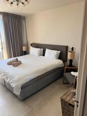 a bedroom with a large bed with white sheets at Dolphin Beach beachfront apartment, 3 bedroom-6 persons in Cape Town