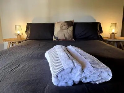 a bed with a blanket on it with two tables at Comfy Greyton Cottage for Four in Greyton