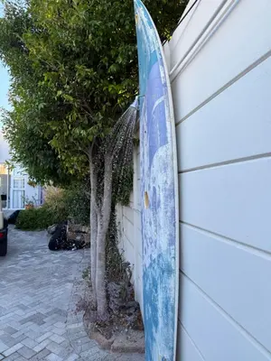 a surfboard leaning against a wall next to a tree at Coastal House - 2BR and Self catering in Cape Town
