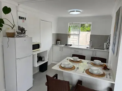 a kitchen with white cabinets and a table with chairs at Coastal House - 2BR and Self catering in Cape Town