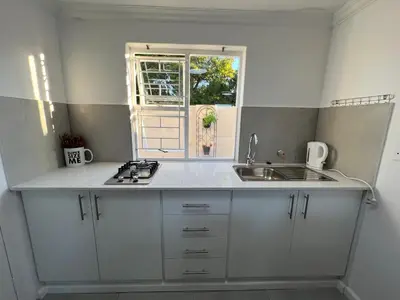 a kitchen with white cabinets and a sink and a window at Coastal House - 2BR and Self catering in Cape Town