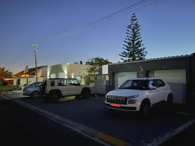 two cars parked in a parking lot next to a building at Coastal House - 2BR and Self catering in Cape Town