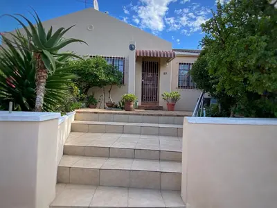 a house with stairs in front of a building at Blouberg Cosy 2 bedroom house in Cape Town