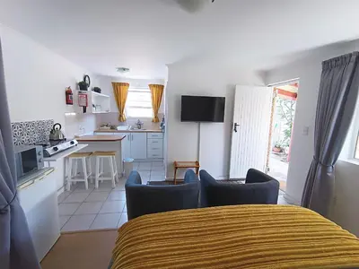 a kitchen and living room with a bed and chairs at NoulAnouk's Corner - Peaceful Studio in Cape Town