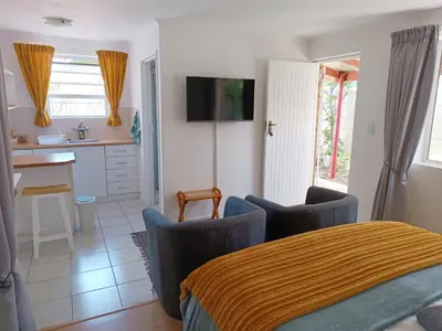a living room with a table and chairs and a kitchen at NoulAnouk's Corner - Peaceful Studio in Cape Town