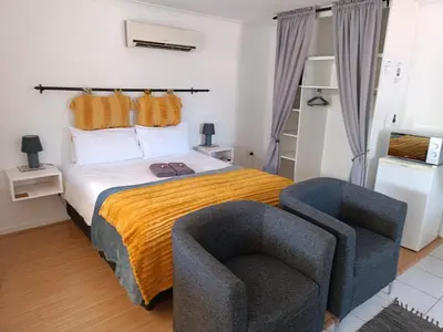 a bedroom with a bed and a chair at NoulAnouk's Corner - Peaceful Studio in Cape Town
