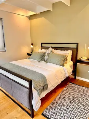 a bedroom with a large bed with white sheets and a rug at Petit Casa Central Stellenbosch in Stellenbosch