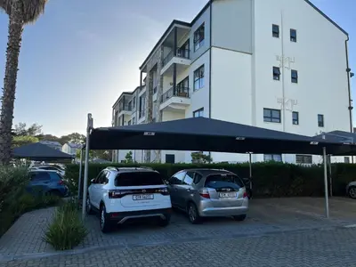 two cars parked in a parking lot in front of a building at Luxury one bedroom apartment in Somerset West