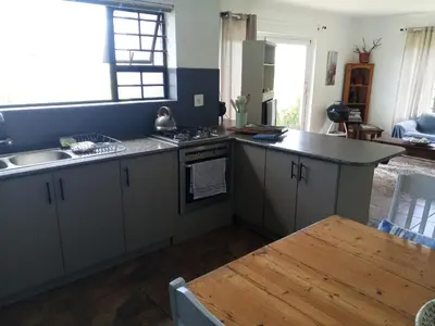 a kitchen with a sink and a stove top oven at Streams Cottage in Bettyʼs Bay