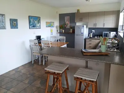 a kitchen with a counter and stools in a kitchen at Streams Cottage in Bettyʼs Bay