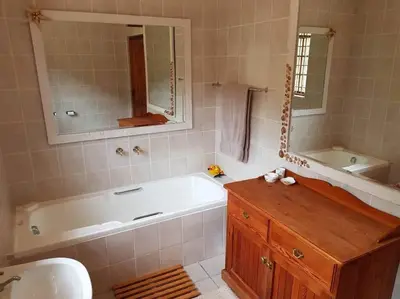 a bathroom with a tub and a sink and a mirror at Witteklip self-catering farm in Kleinmond