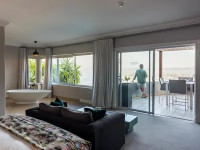 a living room with a couch and a large window at Fijnbos Private Manor in Gordonʼs Bay