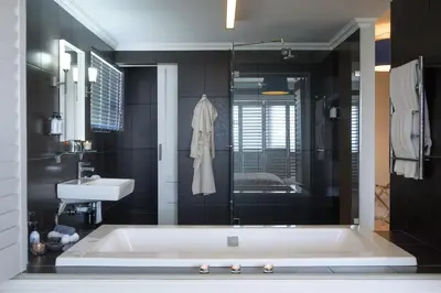 a bathroom with a bath tub and a sink at Fijnbos Private Manor in Gordonʼs Bay