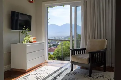 a living room with a tv and a chair and a window at Fijnbos Private Manor in Gordonʼs Bay