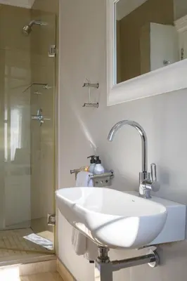 a white sink in a bathroom with a shower at Fijnbos Private Manor in Gordonʼs Bay