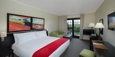 a hotel room with a white bed and a red blanket at The Caledon Hotel and Spa in Caledon