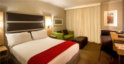 a hotel room with a bed and a green chair at The Caledon Hotel and Spa in Caledon