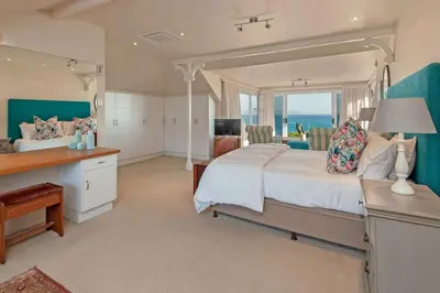 a large bedroom with a large bed and a desk at Wild Waters at Kraal Rock on the cliffs in Hermanus in Hermanus