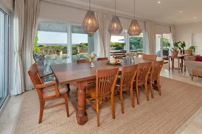 a dining room with a wooden table and chairs at Wild Waters at Kraal Rock on the cliffs in Hermanus in Hermanus