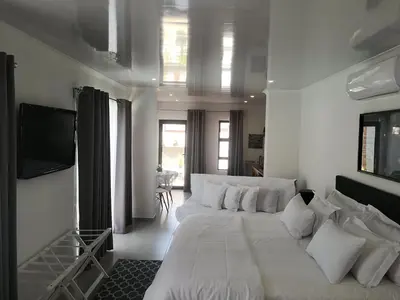a white living room with a couch and a tv at Mi Amor Accommodation in Brackenfell