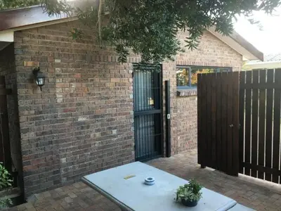 a brick building with a gate and a table in front of it at Aan de weg in Cape Town