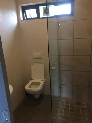 a bathroom with a toilet and a glass shower stall at Aan de weg in Cape Town