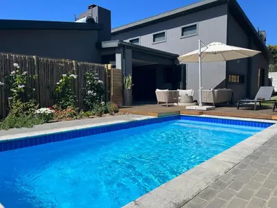 a swimming pool in front of a house at Maîté Iphupho in Somerset West