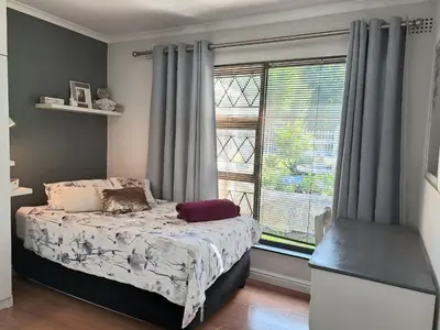 a bedroom with a bed in front of a window at Cosy and Central Family Home in Cape Town