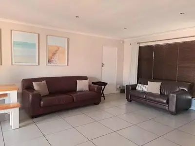 a living room with two leather couches and a table at Cosy and Central Family Home in Cape Town
