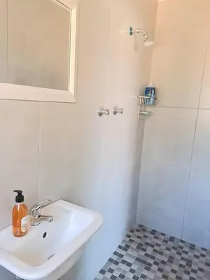 a bathroom with a sink and a shower with a mirror at Cosy and Central Family Home in Cape Town