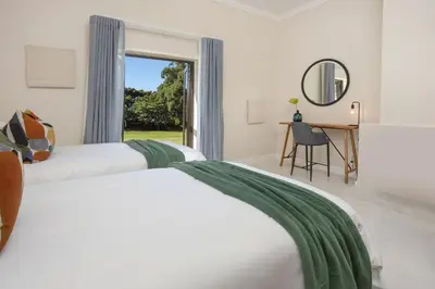 a bedroom with two beds and a desk and a window at Southwinds Estate in Hermanus
